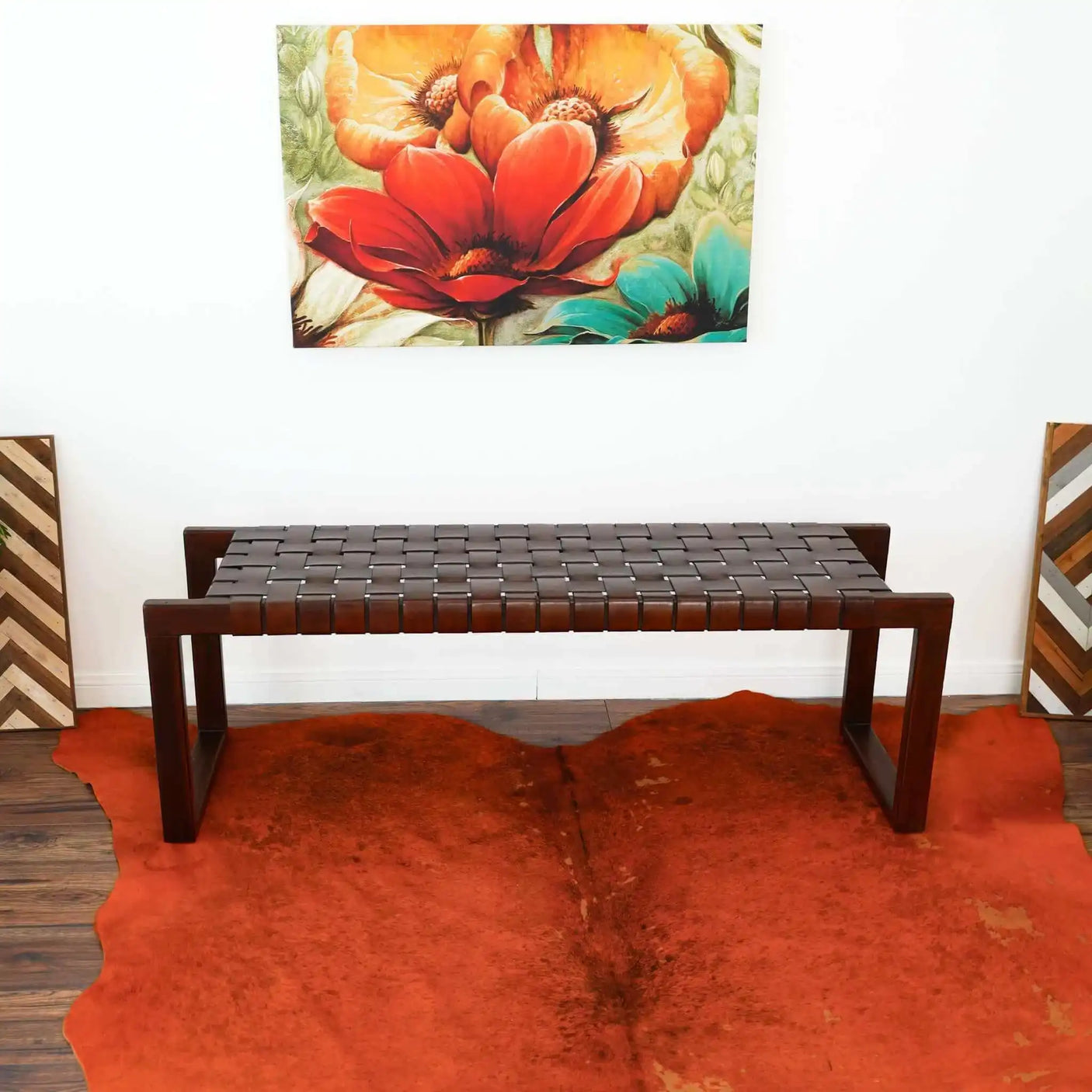 Mid-century modern woven leather bench on orange cowhide rug with floral wall art