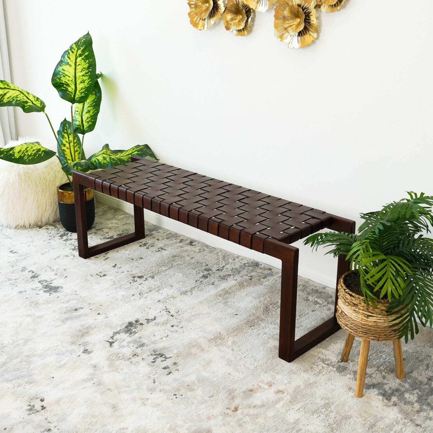 Modern dark wood bench with woven seat, indoor plants, and decorative wall art