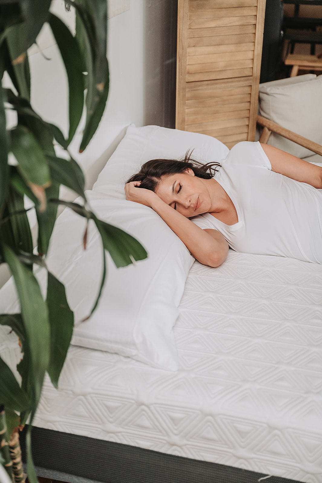 Woman sleeping on a white mattress with geometric pattern in a cozy bedroom
