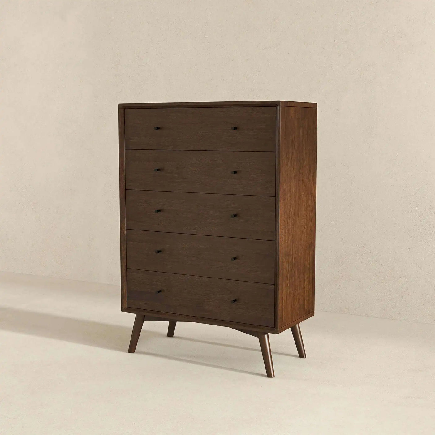 Mid-century modern dark wood dresser with five drawers on angled legs against beige wall