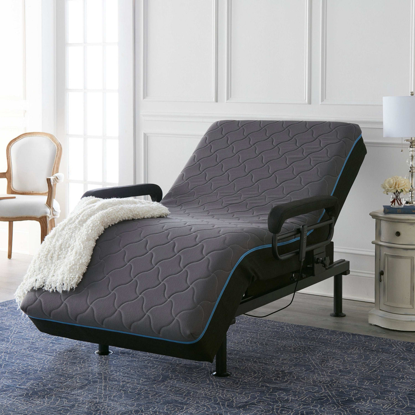 Adjustable bed with gray mattress and armrests in a modern bedroom setting