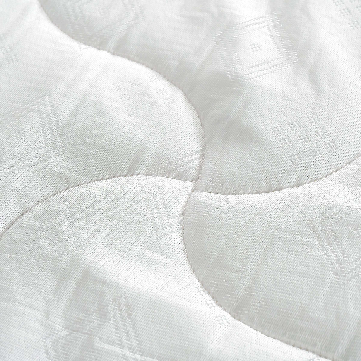Close-up of white quilted mattress fabric with wave stitching pattern