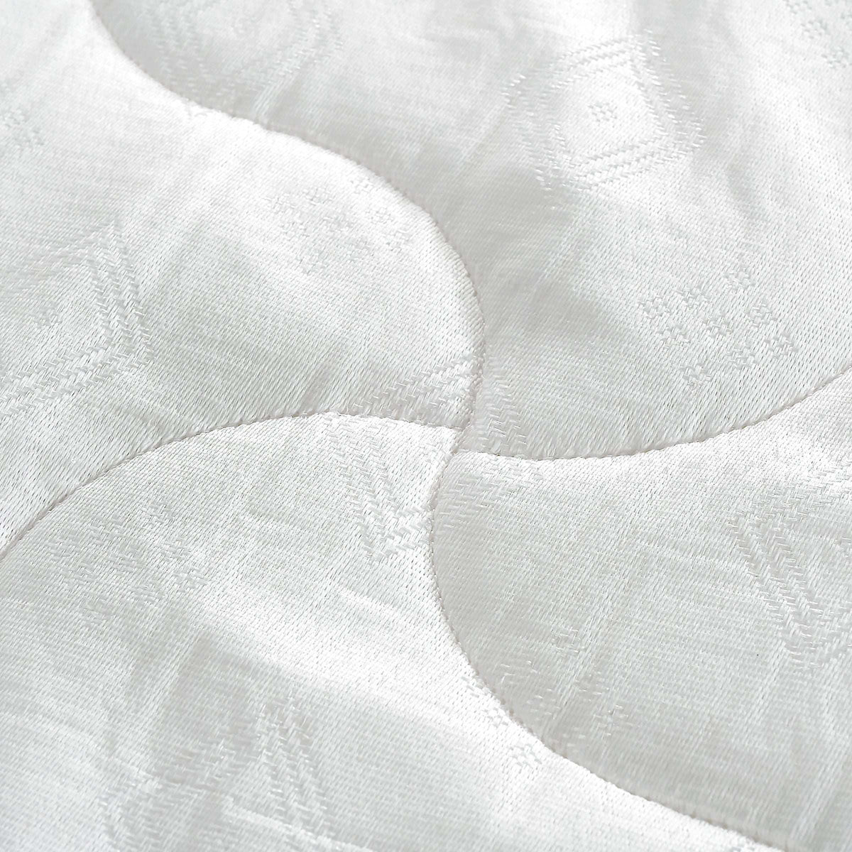 Close-up of white quilted mattress fabric with wave stitching pattern