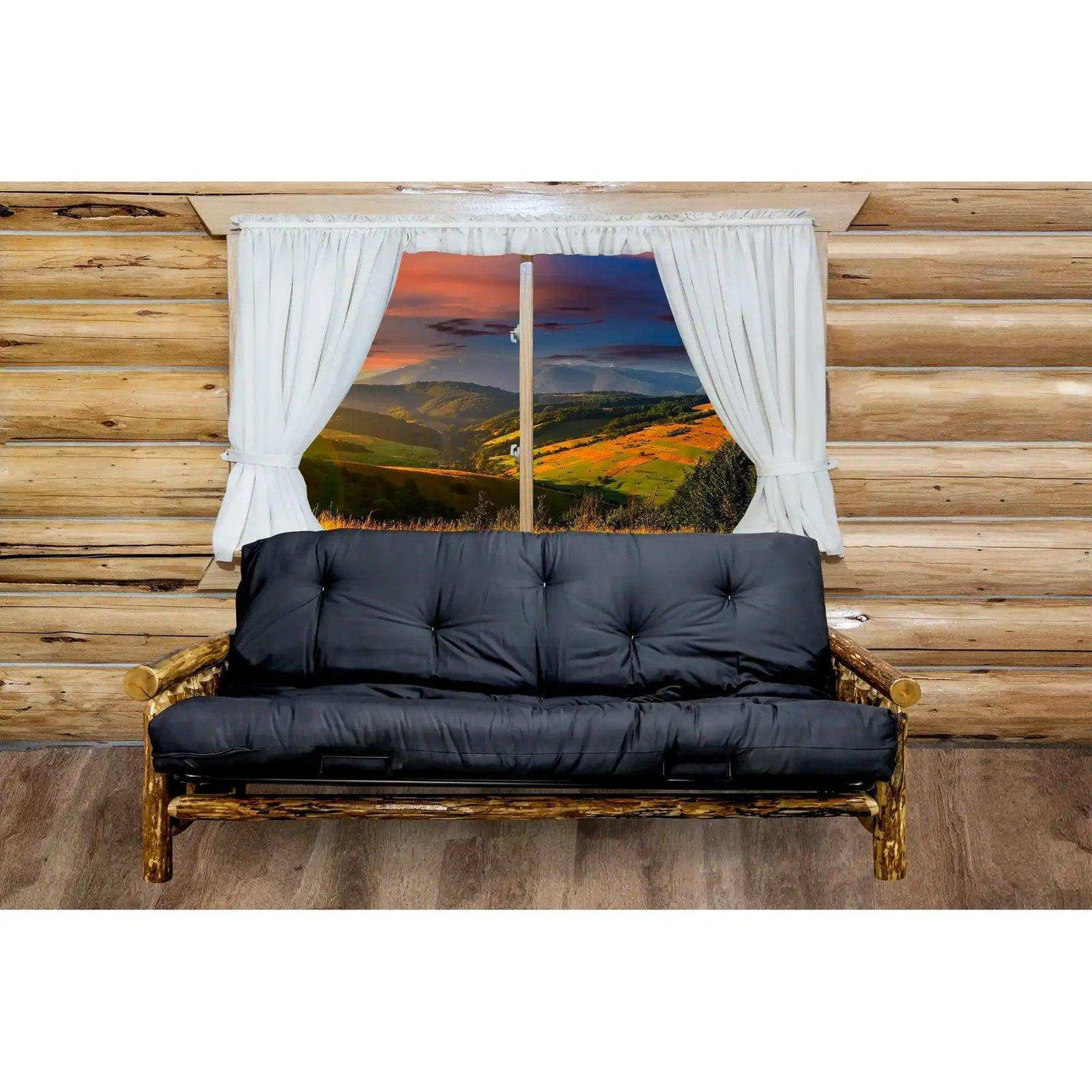 Rustic futon frame with black mattress in log cabin room, scenic mountain view window
