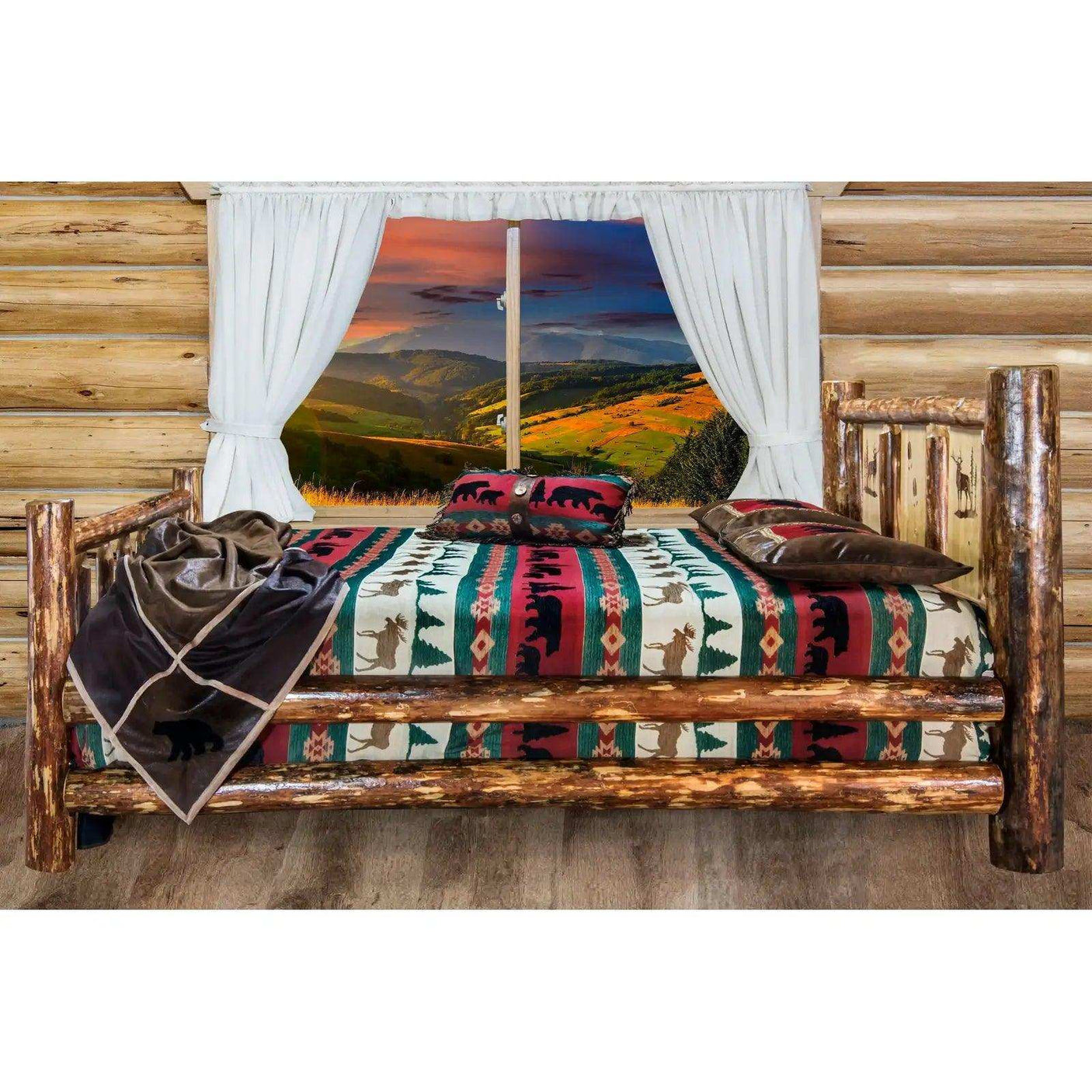 Rustic log king bed with patterned wildlife bedding in a cabin room, mountain sunset view outside window