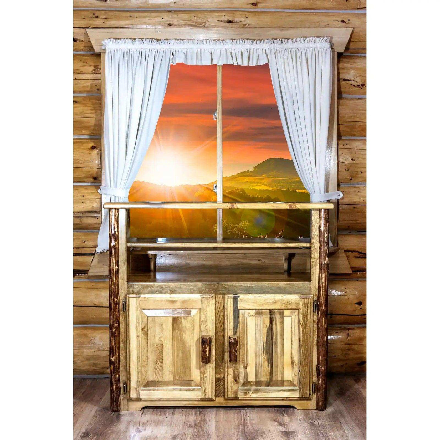 Rustic wood media center in log cabin room with white curtains and mountain sunrise view