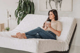Woman relaxing with a mug on adjustable bed with white geometric bedding