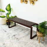 Modern dark wood bench with woven seat, indoor plants, and decorative wall art