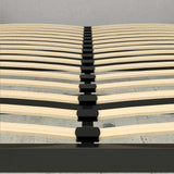 Wooden slatted bed base with black metal frame and plastic connectors on concrete floor