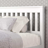 White slatted full bed with light bedding against hexagon pattern wallpaper
